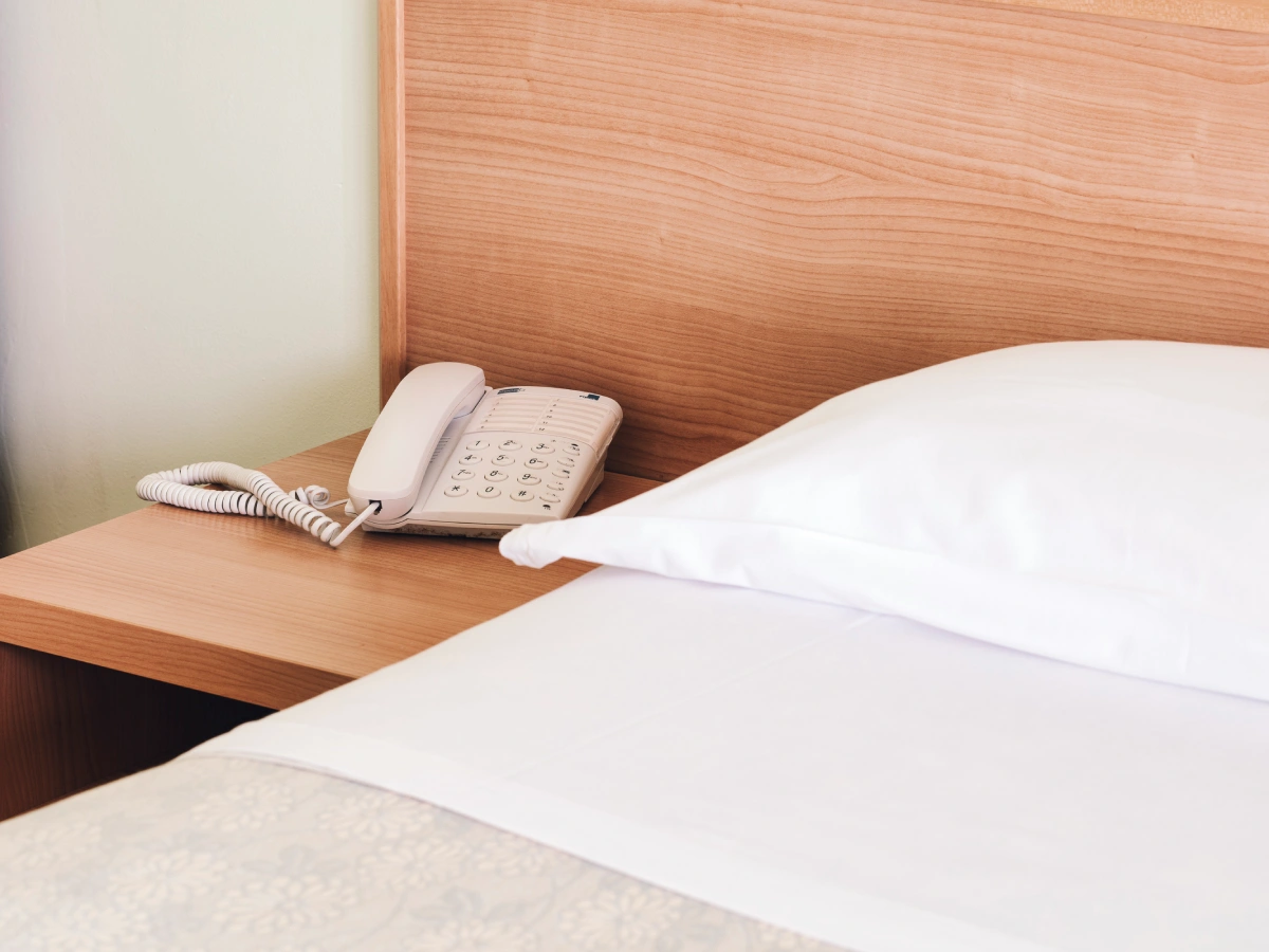 Telefono e porzione di letto con cuscino in camera d'albergo