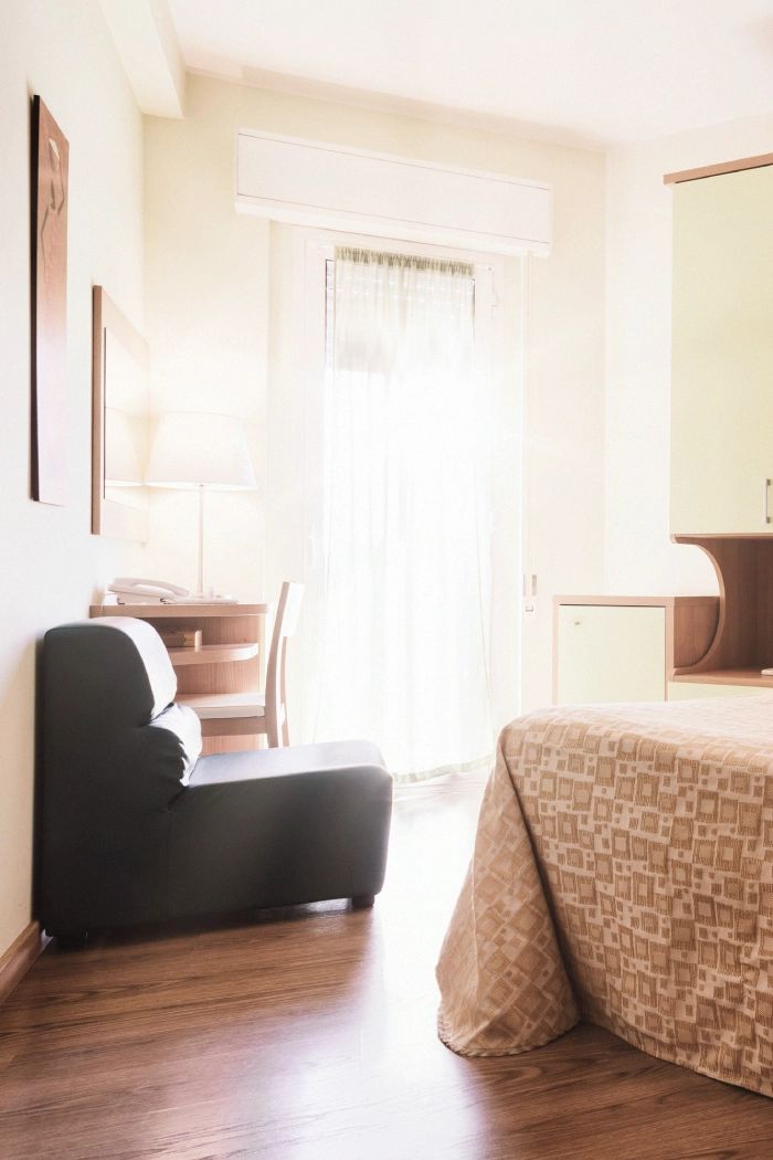 porzione di camera con un divano, una porzione di letto e una finestra