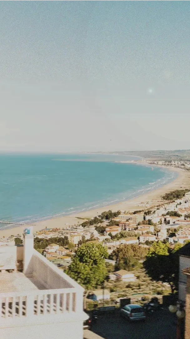 Veduta soleggiata sul golfo di Vasto con alberi, auto e il mare